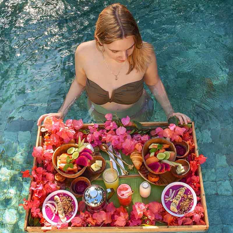 Mujer desayunando en la piscina en Bali