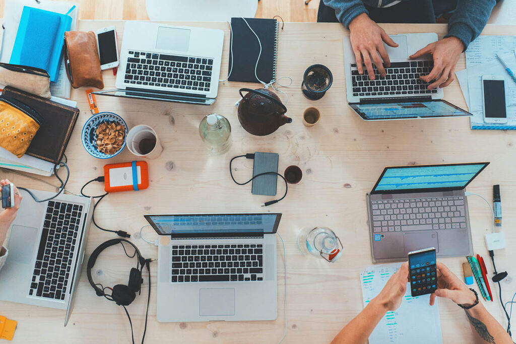 Cinco ordenadores portátiles con personas trabajando