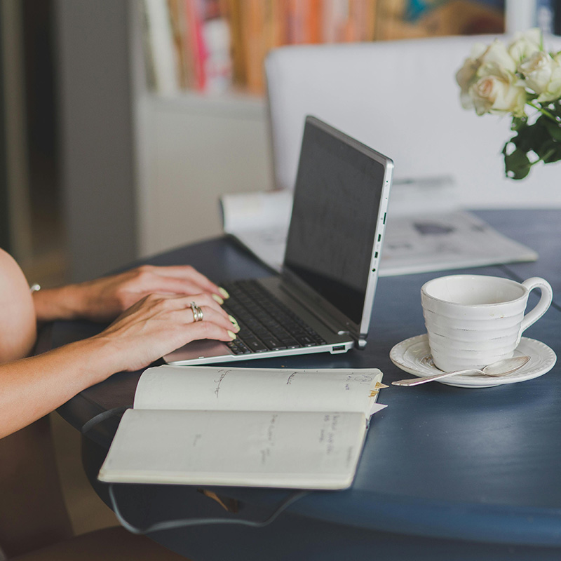 Mujer trabajando con un ordenador portátil, un cuaderno y una taza de café