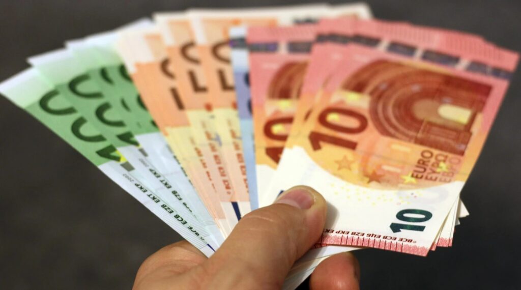 Mano sosteniendo varios billetes de euro en abanico, simbolizando las estafas en las que se solicita dinero por adelantado para obtener un trabajo remoto.