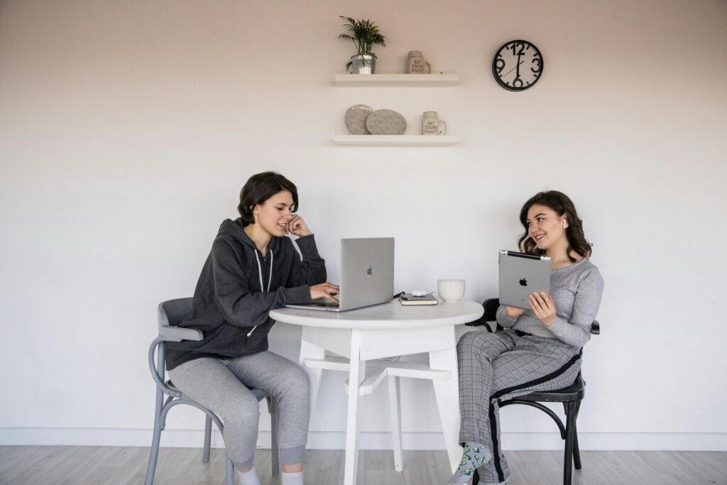 Dos mujeres con ordenador y tablet trabajando en chándal