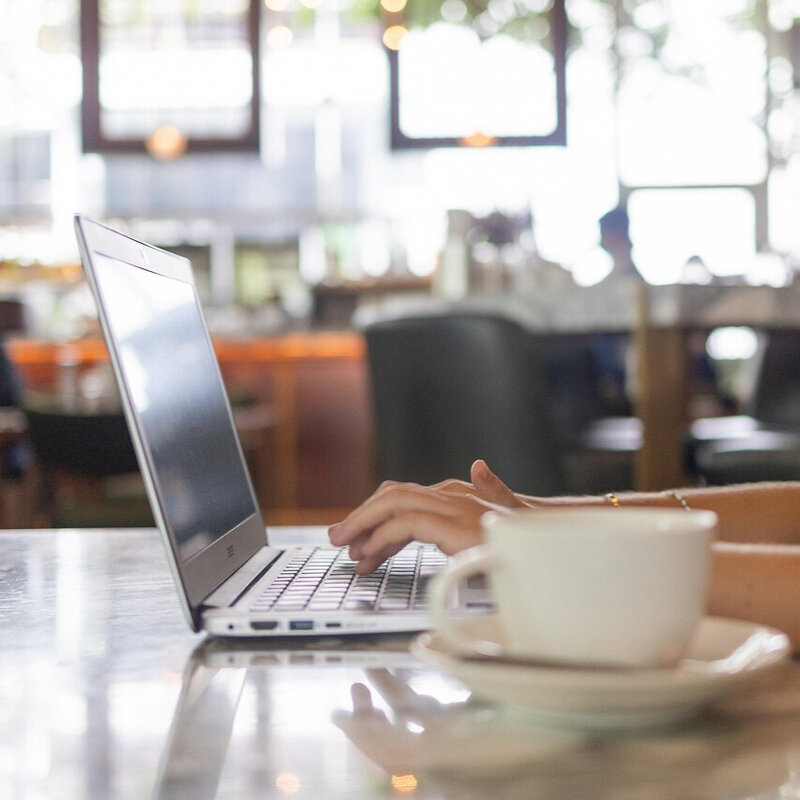 Persona trabajando en un ordenador portátil con una taza de café